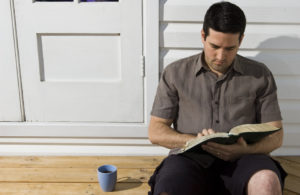 Man sitting on floor with a book and coffee to represent quiet time