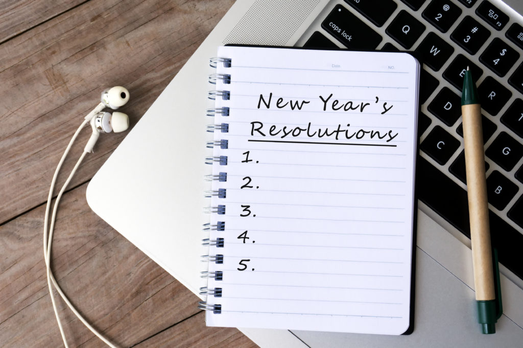 New Year's Resolutions notebook sitting on keyboard to represent sales leader resolutions